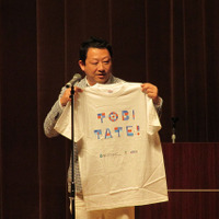 プロジェクトリーダー船橋力氏による「TOBITATE」Tシャツの紹介には会場からどよめきも　撮影：佐久間武