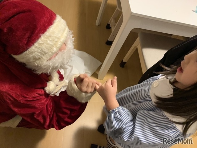 クリスマスに、子供を訪問したようす。サンタから本を渡しつつ「キミのことを見守っていたよ」と伝える