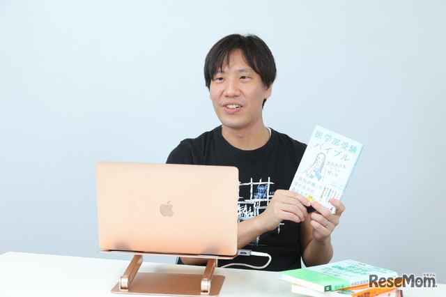 自身の著書『医学部受験バイブル』(幻冬舎)を手にインタビューに応える高梨氏
