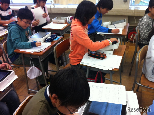 写真2　友達のリーフレットをiPadで開いて学ぶ子どもたち