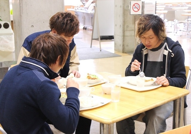 成城大学の学食内で、試食用のメニューを食べている学生たち