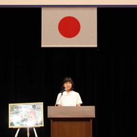 朗読中の井崎英里さん。横には、自身が描いた絵が飾られている
