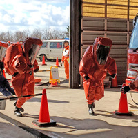 工場での災害を想定した「特殊災害中隊連携訓練」の様子。化学防護服で工場に突入する消防隊員。