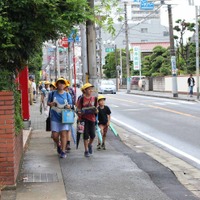 子どもたちが通る道では、黄色いシャツを着たスタッフが見守っている