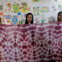 技術研修で藍染を学び完成品のスカーフを掲げる少女たち