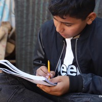 ノートを見返すシリア難民の男の子（レバノンの難民キャンプ）