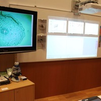 電子黒板、PC、大型テレビ、デジタル顕微鏡、メディアプレーヤーなどが用意された教室。生徒の机にはタブレット
