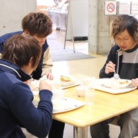 成城大学の学食内で、試食用のメニューを食べている学生たち